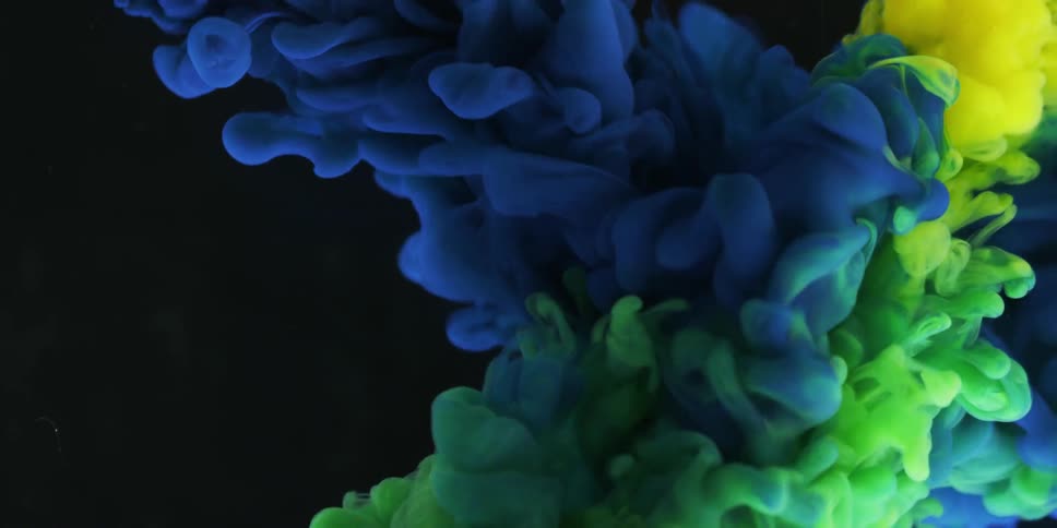 Blue, green and yellow liquid pours into clear liquid