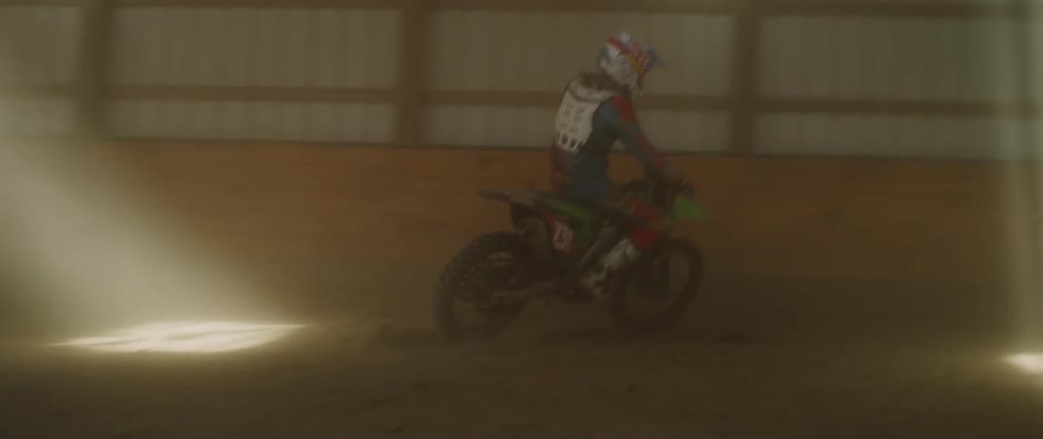 Person rides a dirt bike on an indoor track