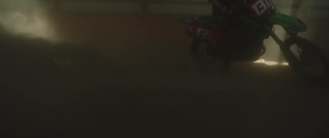 A man is riding a dirt bike inside a barn in daylight