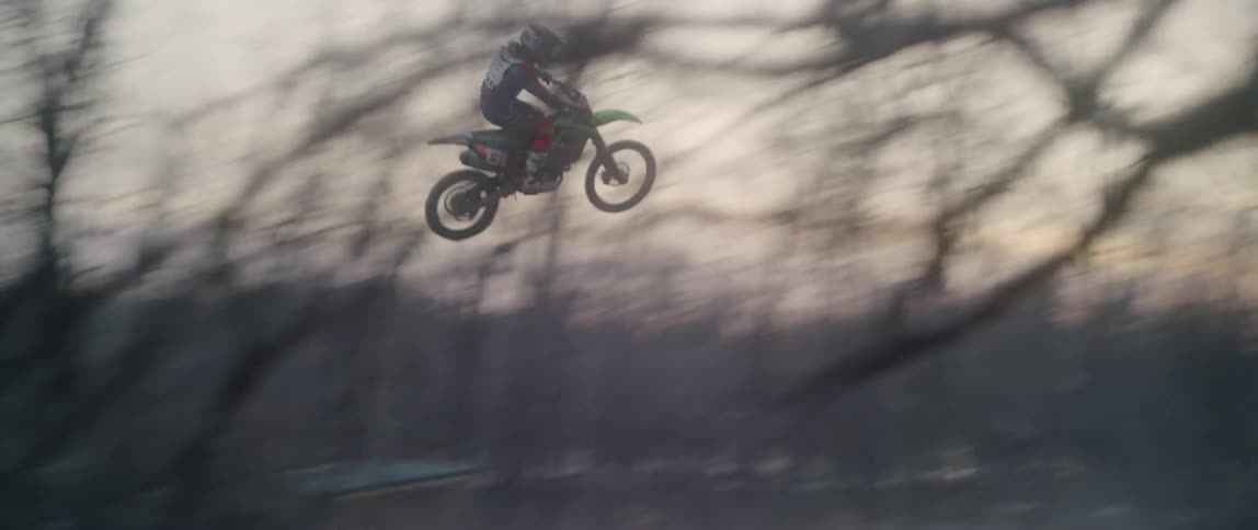 A dirt bike rider jumps off a dirt ramp