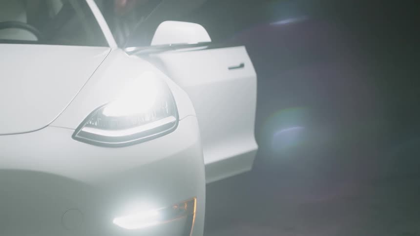 A white sports cars lights flash up as it is unlocked