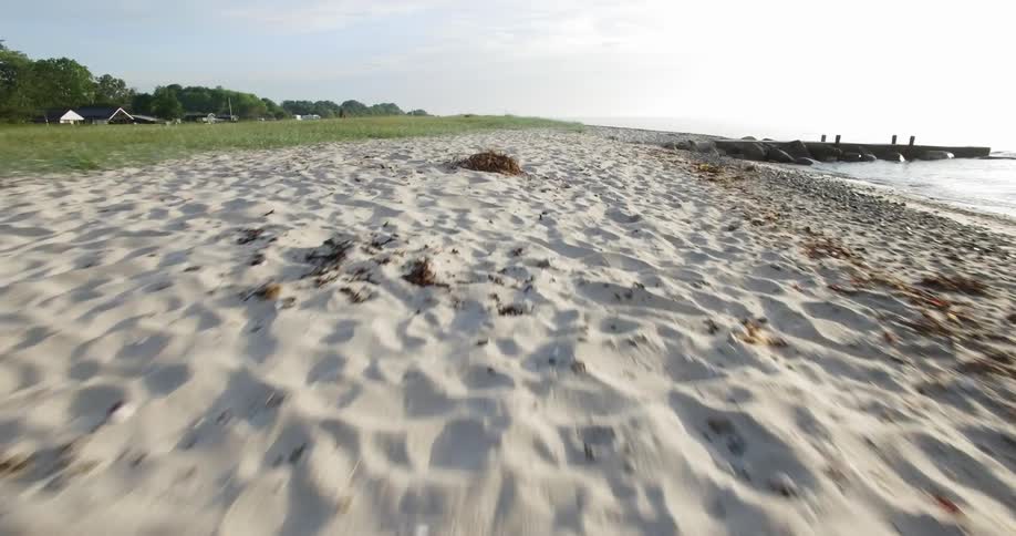 Waves are lapping a beach in a coastal community during the day