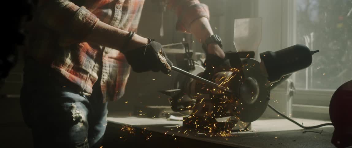 A man is using a saw to cut a metal bar inside in daylight