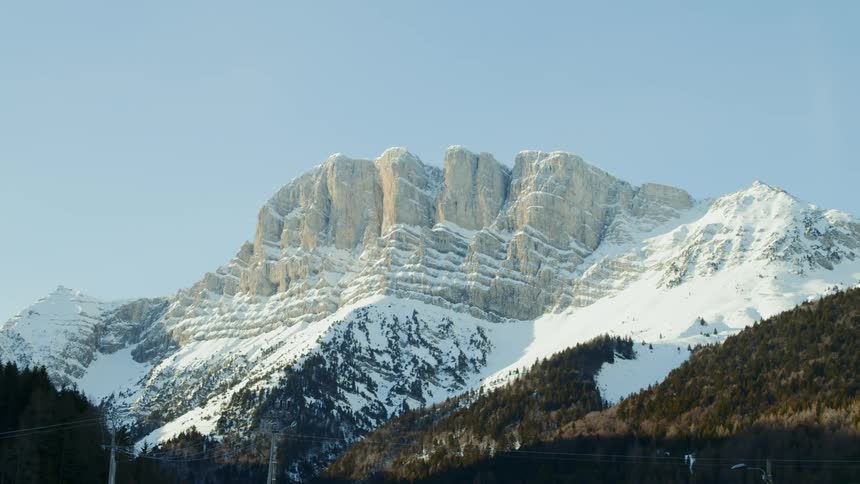 Snow surrounds a rocky cliff in the mountains