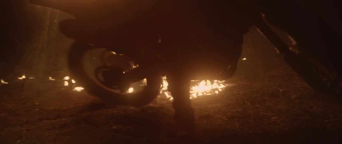 A dirt bike rides up to a burning fire
