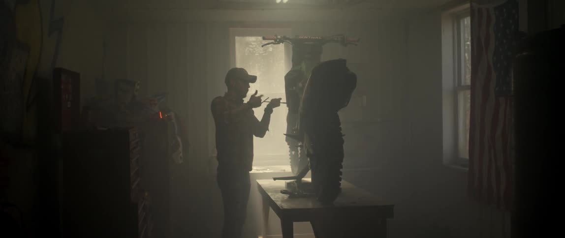 A man repairs a dirt bike in a garage