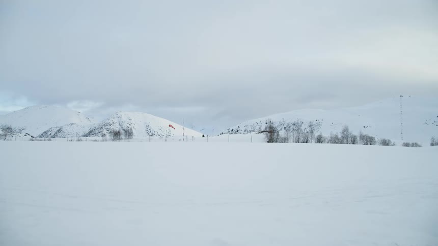 Large flat area of snowy land with hills in the background