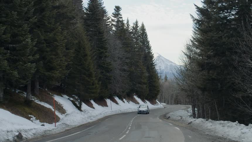 A vehicle travels on a snowy mountain road
