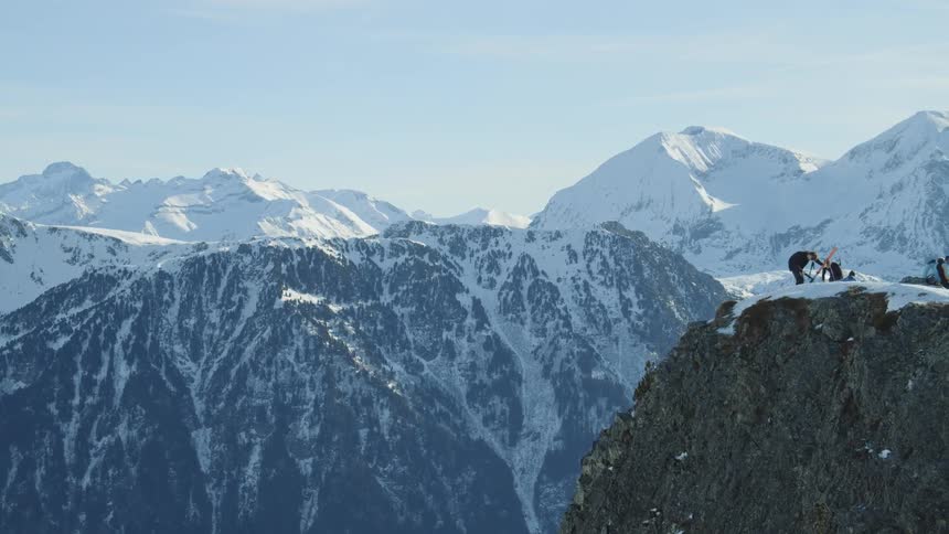 Skiers stand on a snowy mountain peak