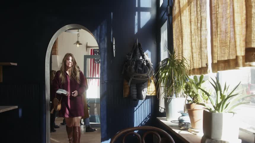 A woman walks through a doorway carrying a book