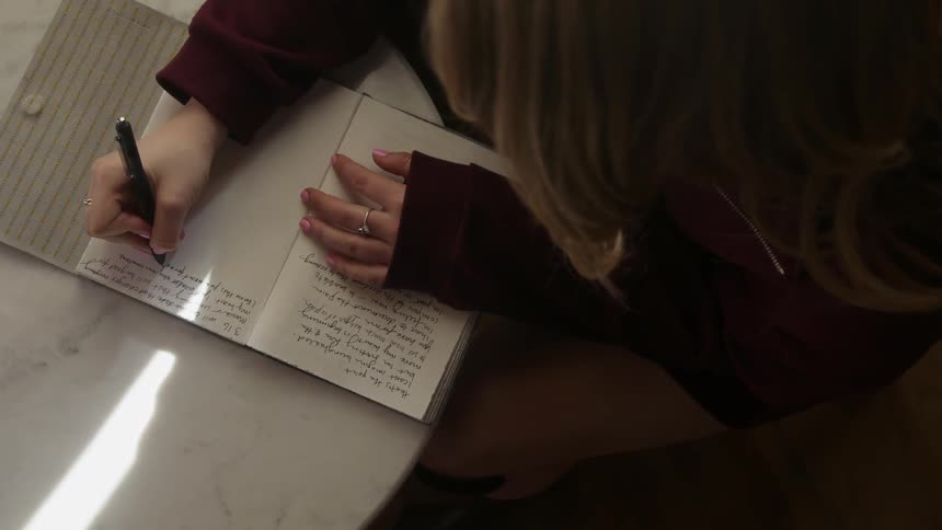 Woman writes in a journal at a desk