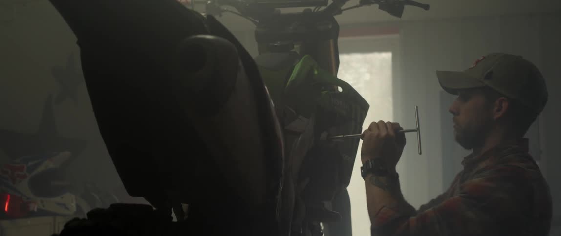 A man uses a wrench on a dirt bike