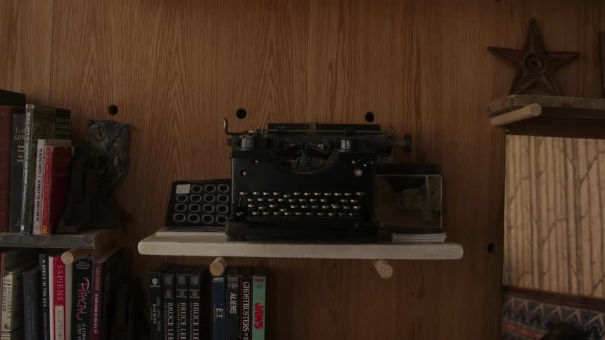 A typewriter sits on a shelf near books