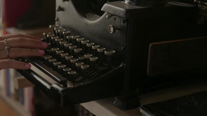 Woman runs her fingers over the keys of an old typewriter