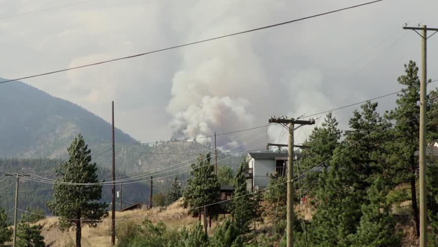 Smoke billows from a hilltop on a windy day