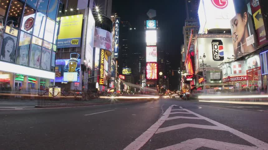 Cars drive down a busy city street at night