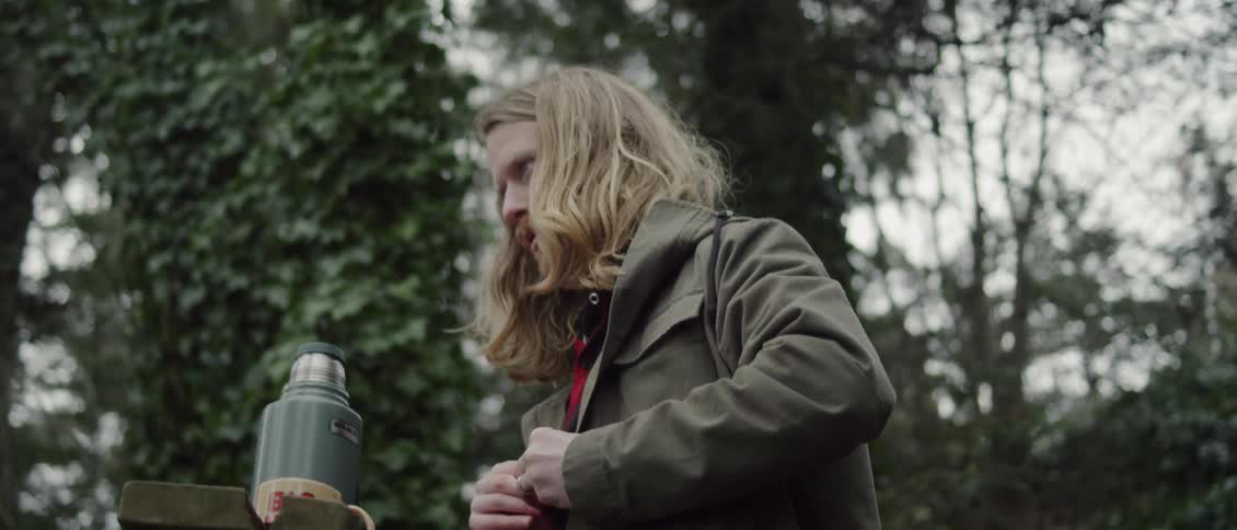 A man unbuttons his jacket outside