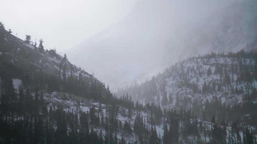 Snow flurries are blowing in a mountain valley during the day