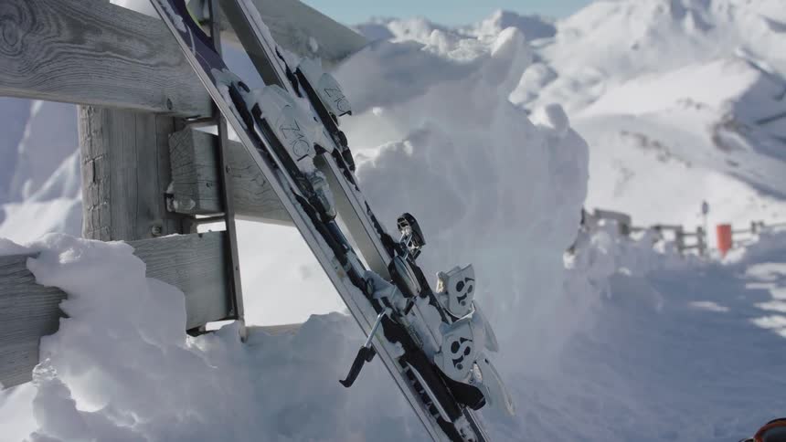 Two skis lean against a wood structure