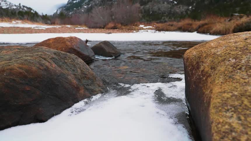 River water is flowing beneath melting ice in daylight
