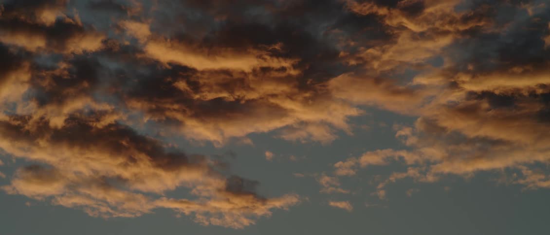 Clouds hang in the sky as the sun sets