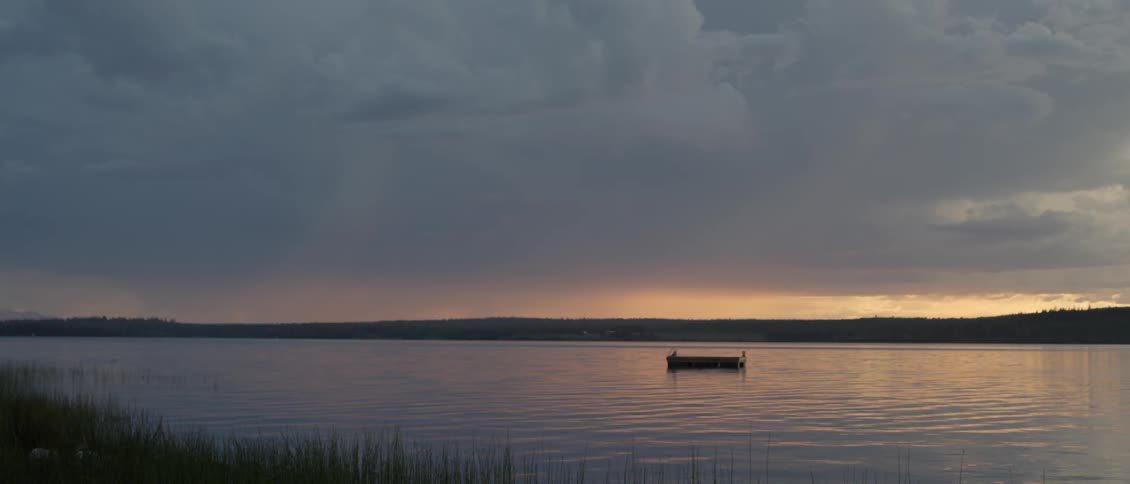 A swim raft floats in the water at sunset