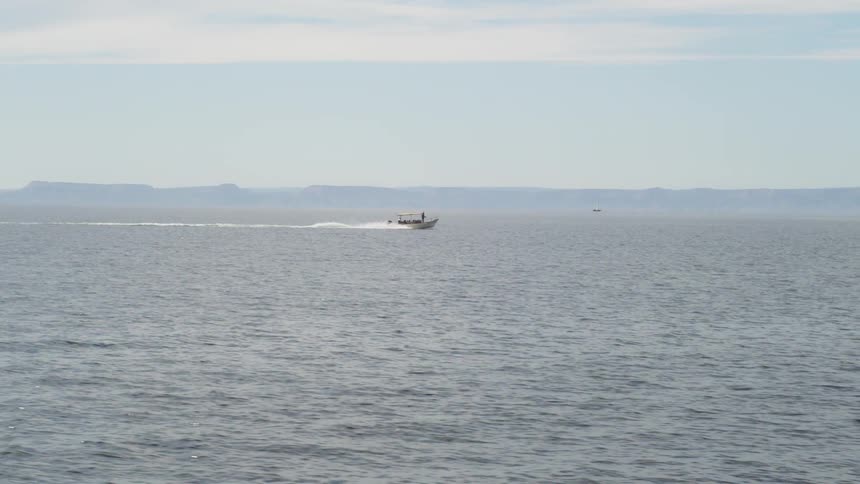 A motorboat is traveling across the ocean on a sunny day
