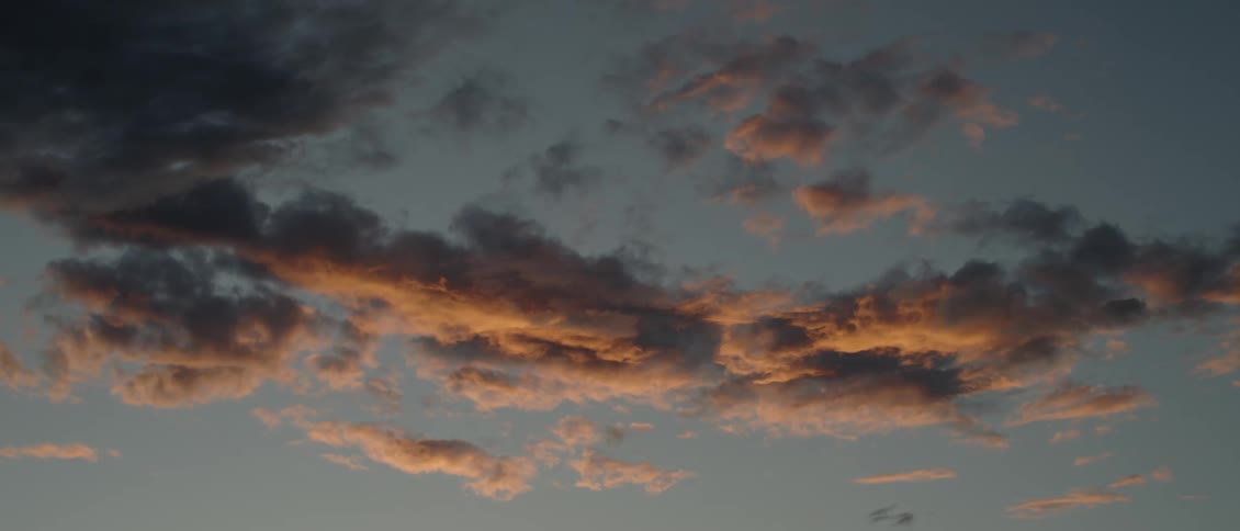 The sunset's glow is shining on clouds in the sky