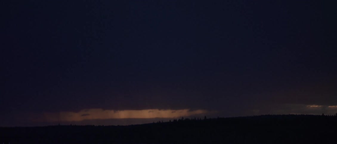 Lightning streaking in the sky with a storm in the distance