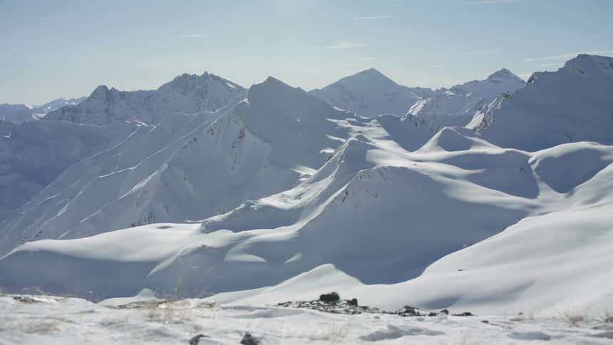 Snow is covering the slopes of a mountain range during the day