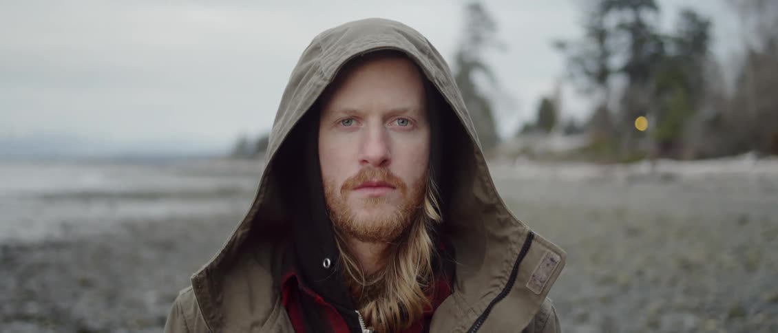 A man is standing on the beach staring forward