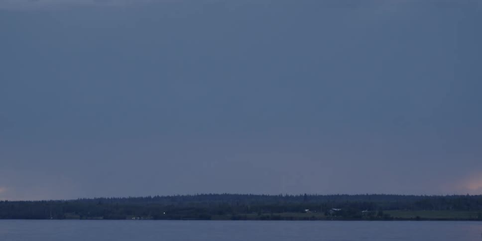 Lightning flashes over a large body of water and shoreline
