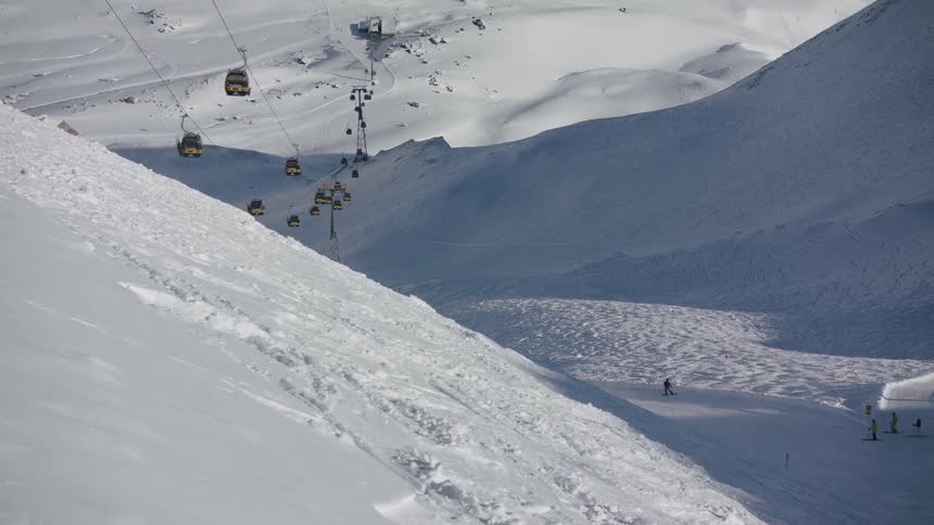 Gondola running and people skiing on snow covered mountain