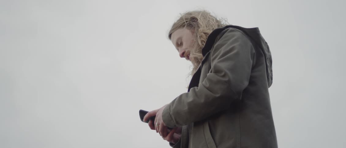 Man is looking at cell phone outdoor on breezy and overcast day