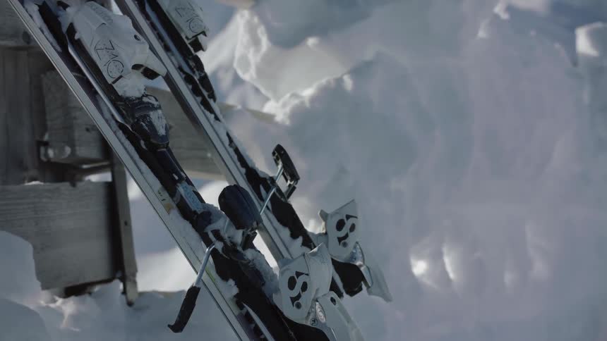 Two skis lean against a wood structure