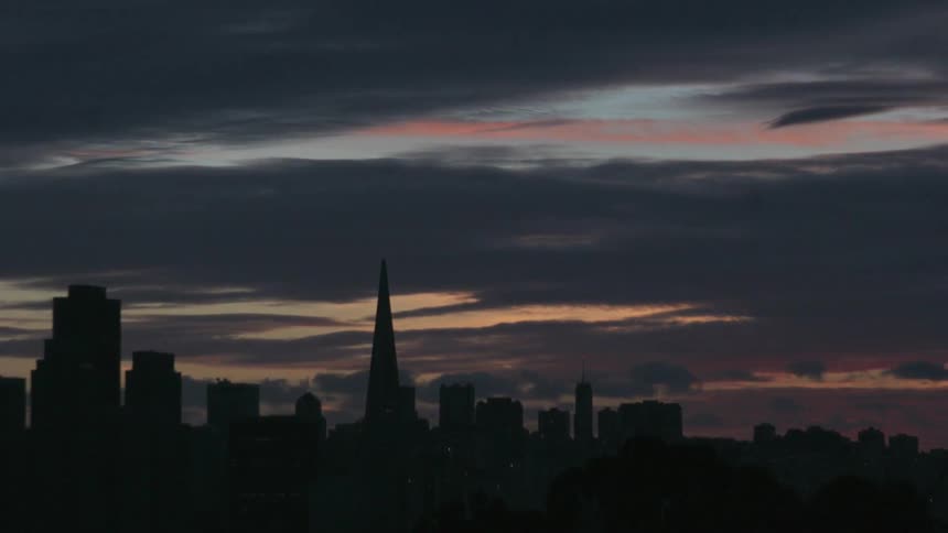 Time lapse of clouds moving in to cover a city during sunset
