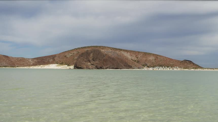 Brown hills beyond a beach on a cloudy day