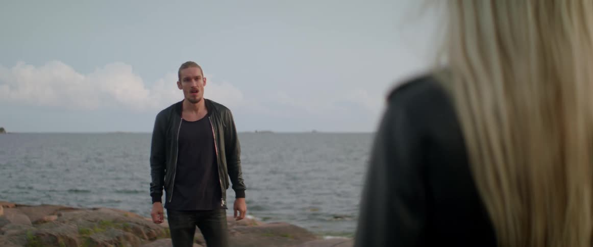 An upset traveler shouts aggressively during a heated outdoor relationship fight near water.