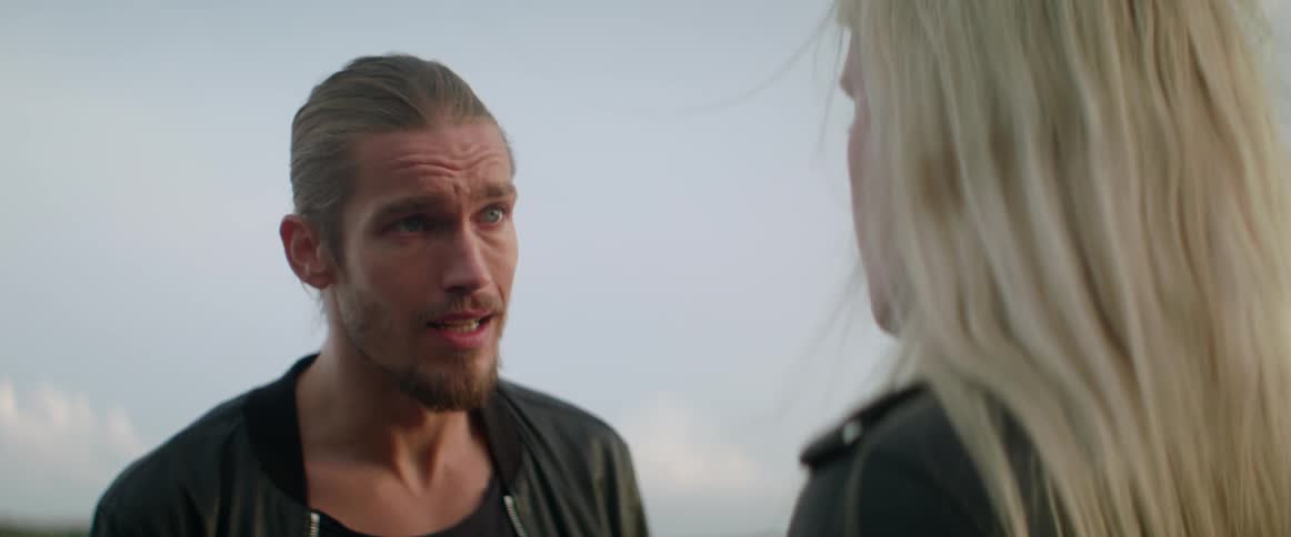 An unhappy couple has a tense and emotional relationship conversation under a grey sky.