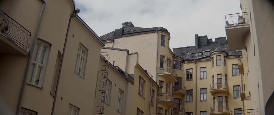 Traditional European residential buildings stand close together under a grey cloudy sky outdoors.