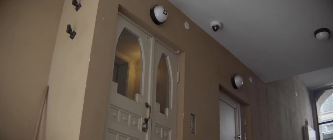 Outdoor security cameras monitor the entry porch of a traditional European house block.