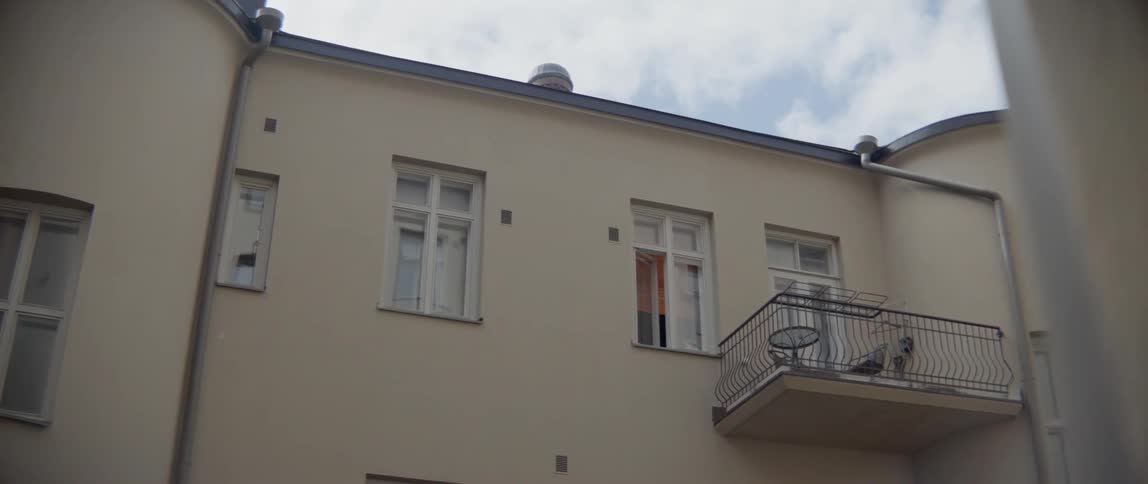 A classic European residential building features small windows and a metal terrace railing.