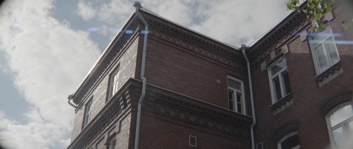 Classical masonry details decorate the roofline of a historic apartment block during daytime.