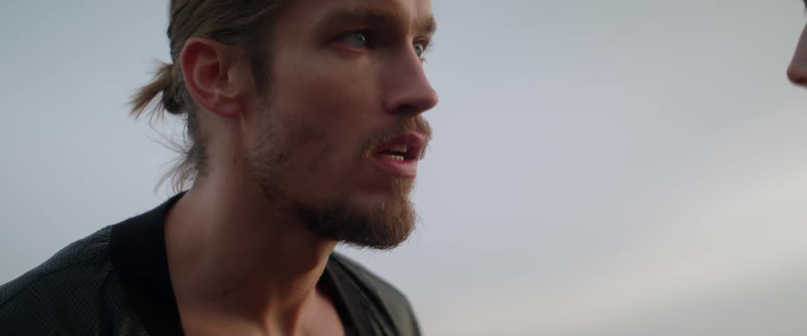 A furious boyfriend yells aggressively at his partner while standing outside at dusk.