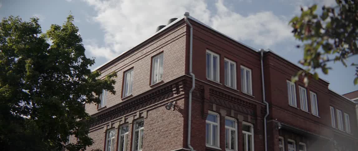 A classic two story brick building features white window frames on sunny afternoon.
