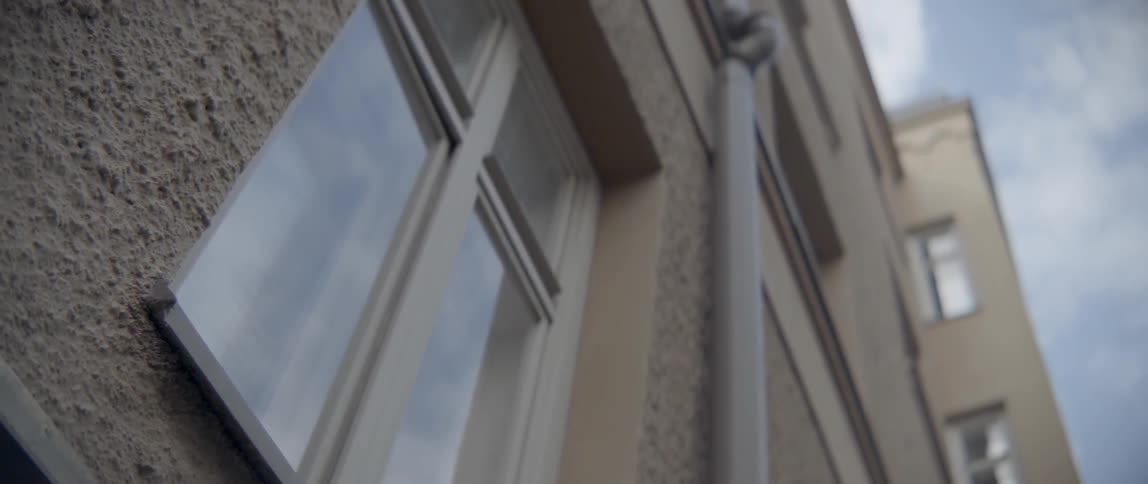 A white framed rectangular window sits on a textured concrete city building facade.