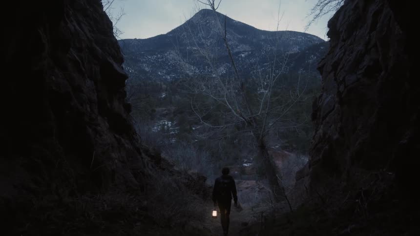 A man walks inside a cavern with a lantern