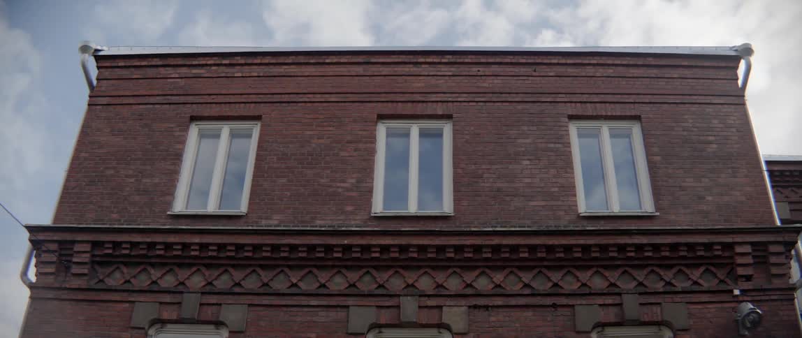 Rectangular windows reflect the blue summer sky on historic brick architecture in town.