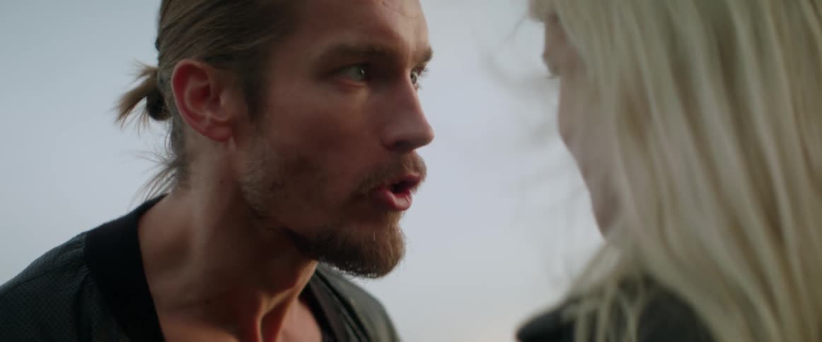 An angry man yells aggressively at his girlfriend during an intense outdoor argument.