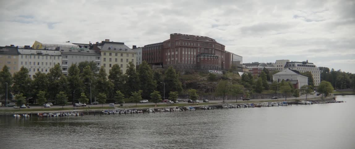 Leisure boats rest along a stone promenade next to a flowing city waterway.